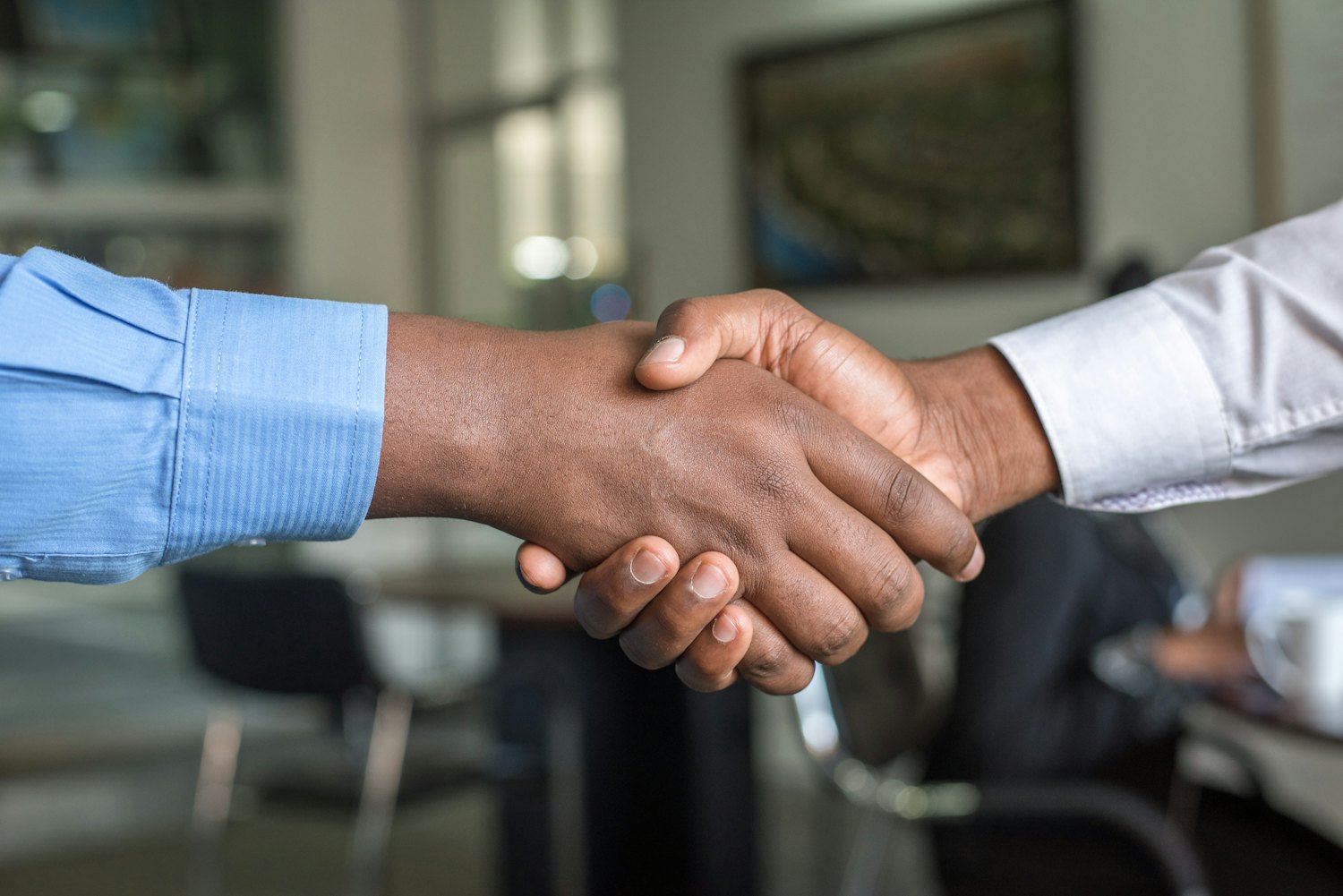 Two people shaking hands across a table after agreeing an offer